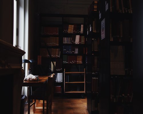 A modern pen laying horizontally on an open canvas paper block inside a quiet bright library room
