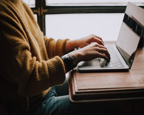 A focused individual typing thoughtfully on a modern laptop during a planned home-office pause